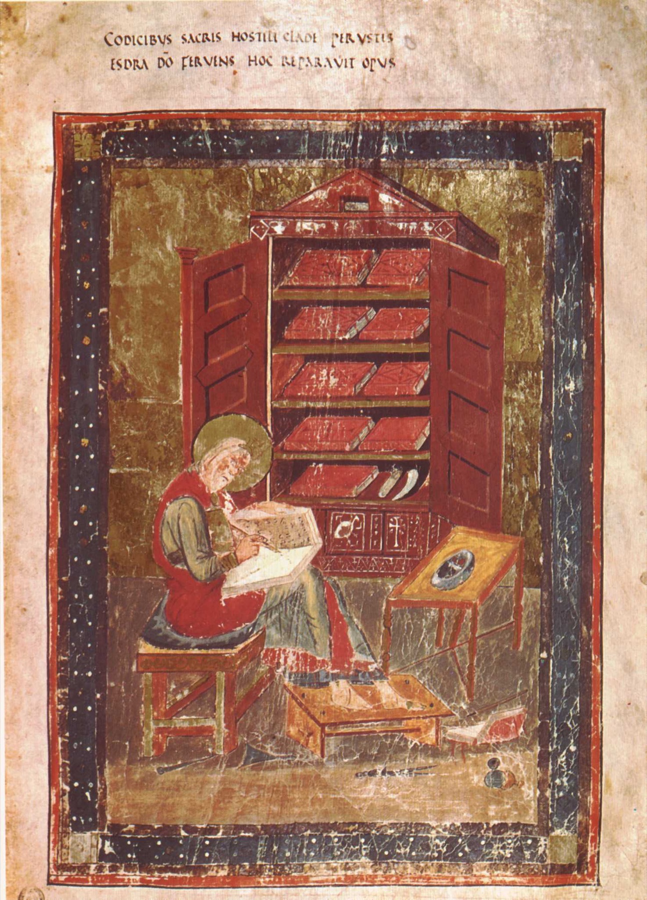 Full-page miniature of Ezra the scribe writing at a desk, with an open cupboard of nine bound books behind him
