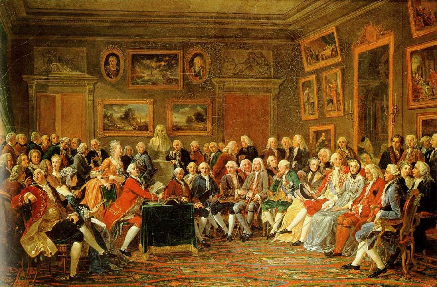 A crowded eighteenth-century salon: a man reads aloud from a manuscript at a small table while dozens of elegantly dressed men and women listen, seated in a semicircle beneath a bust and framed paintings