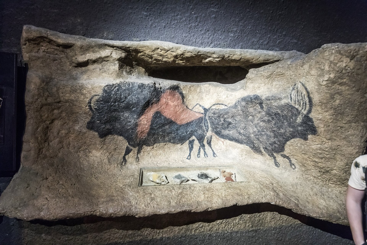 Painted bulls on a cast rock surface inside a constructed gallery, the artificial edge of the cast visible at the bottom
